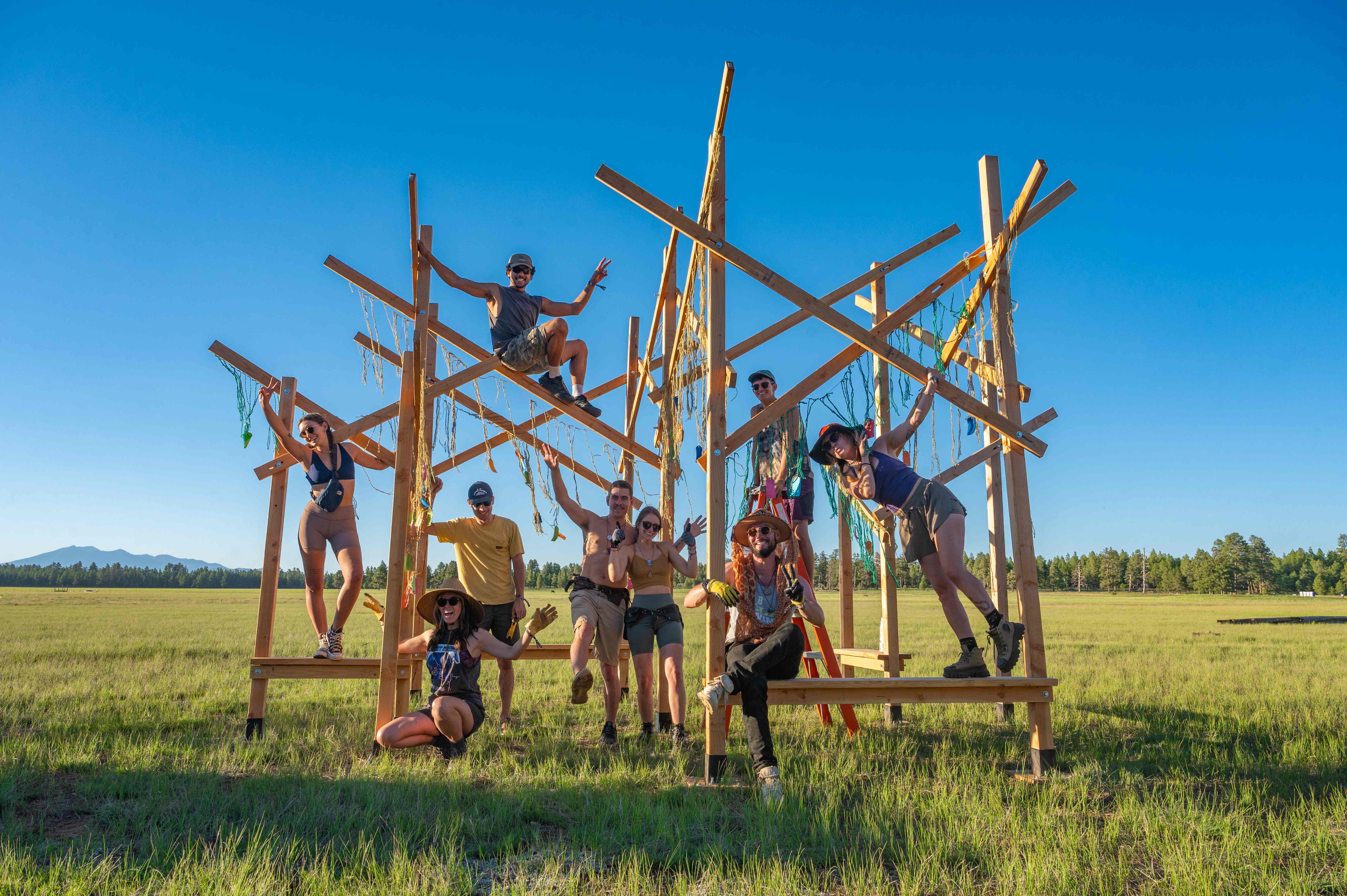 Gratitude Grove build team posing on the installation in a green field