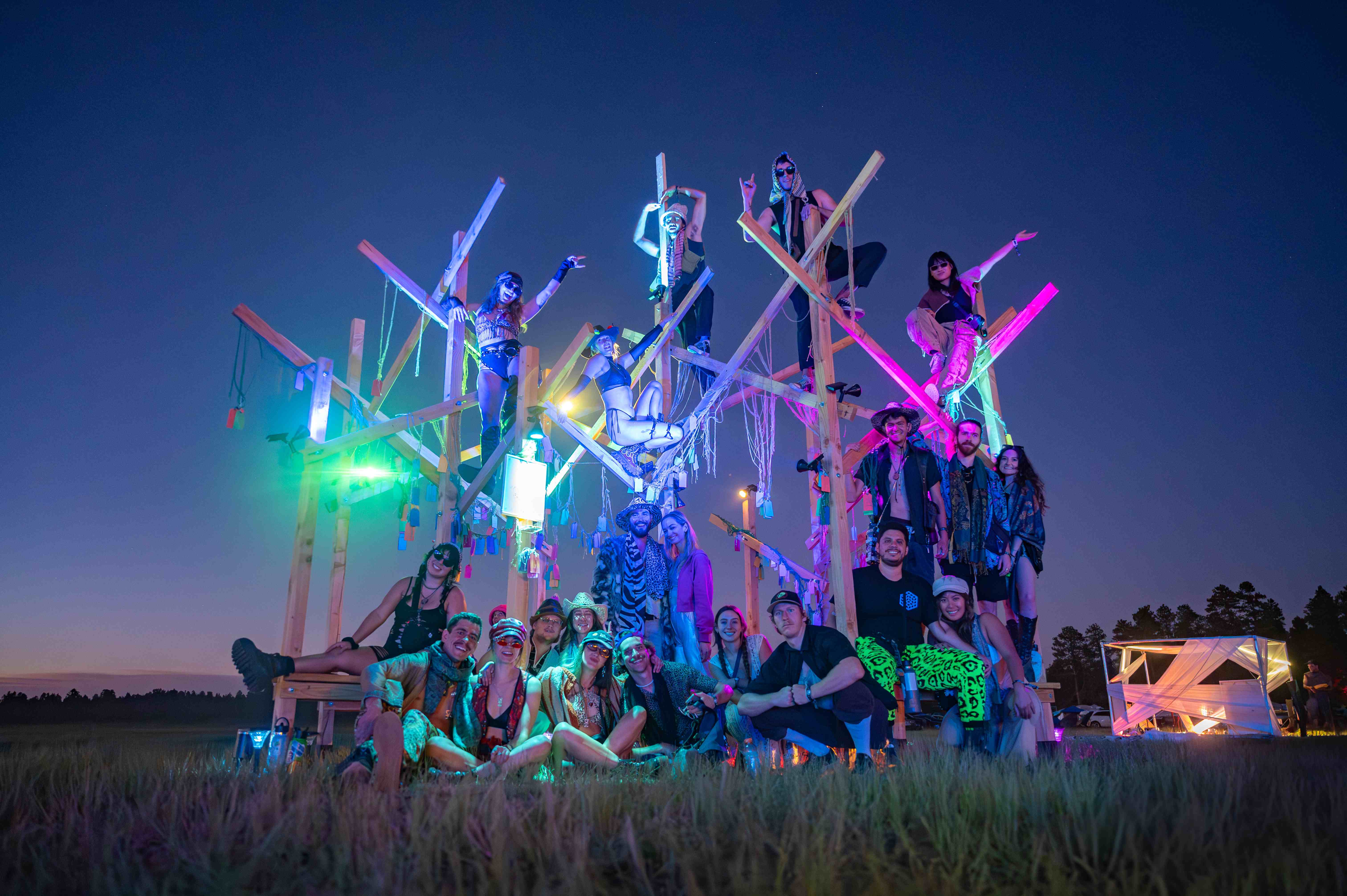 Gratitude Grove lit up at night with colorful lights and the full crew